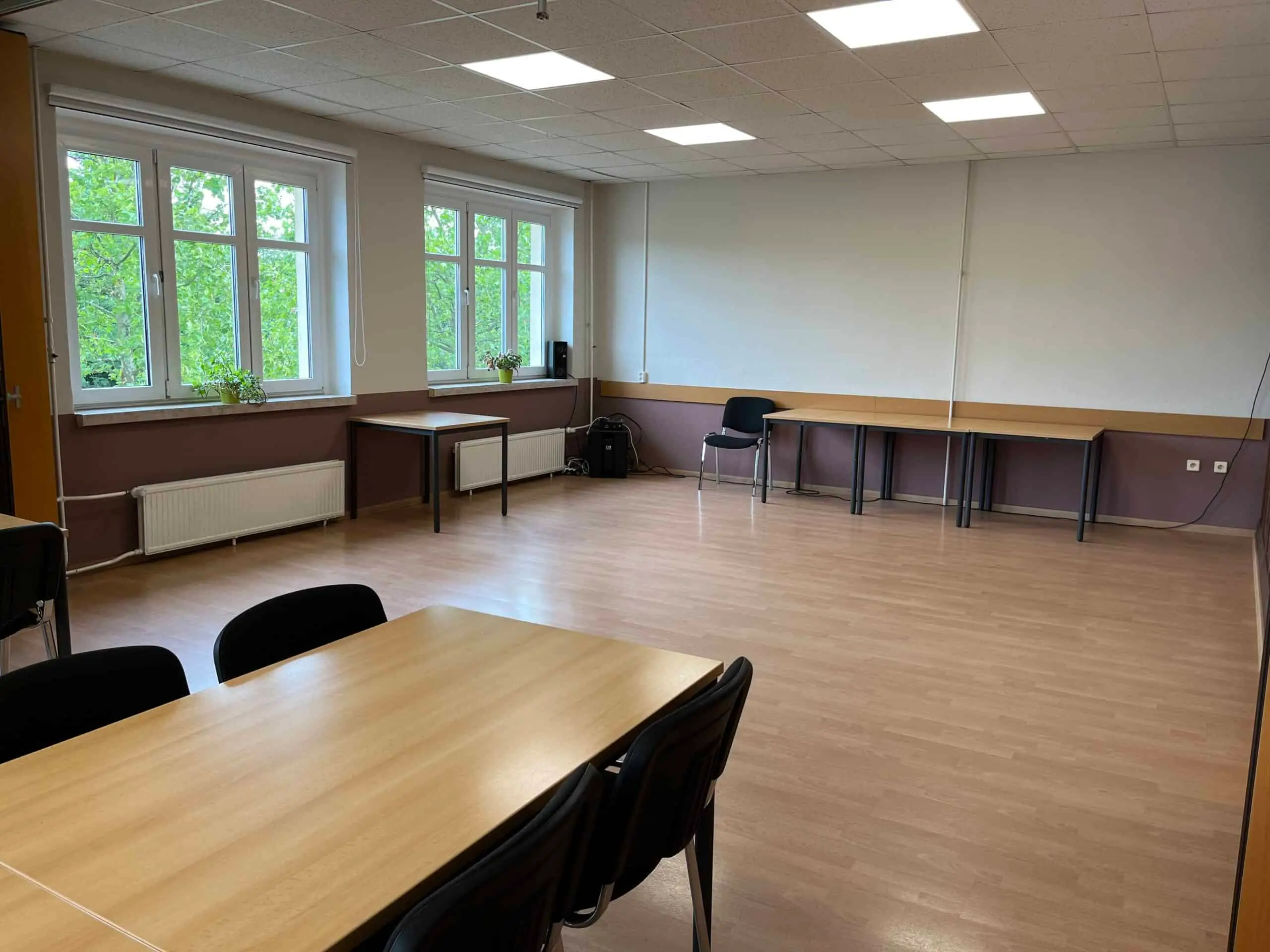 Der leergeräumte Saal mit Laminatboden und einzelnen Tischen an der Wand
